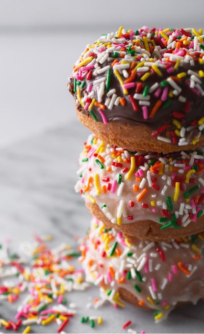A vertical stack of flazed donuts with rainbow sprinkles